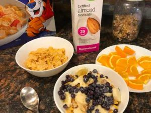 vegan breakfast: cereal with blueberries, bananas and walnuts with almond milk and cut up oranges
