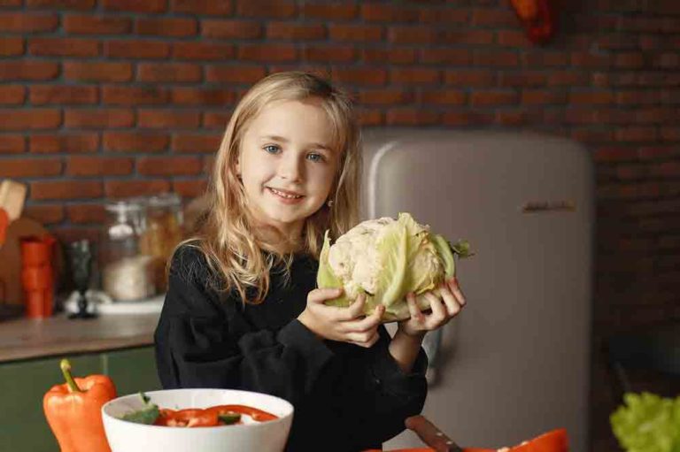 girl with cauliflower How to Teach Kids to Cook Vegan during Covid19. Let your kids help cook in the kitchen and teach them important life skills. Print this guide and kitchen activity book to help make working in the kitchen extra fun! Build on your skills and keep track of your progress.
