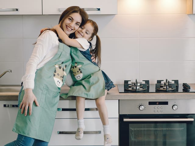 mom and child with green aprons in kitchen