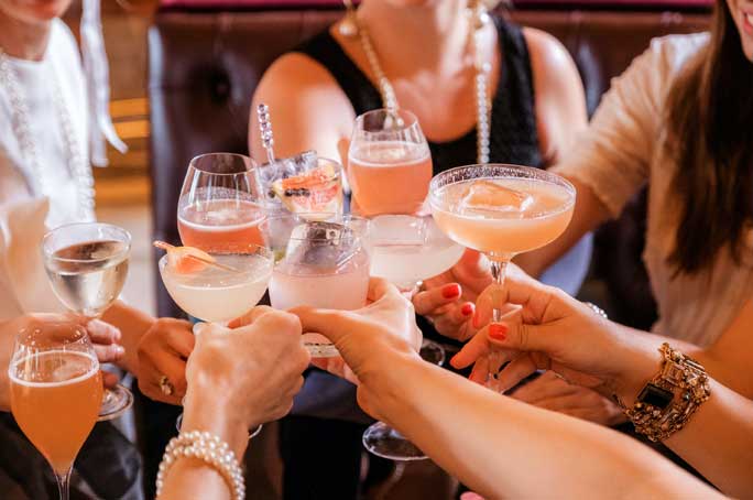 women toasting with fancy cocktail drinks in long stem glasses