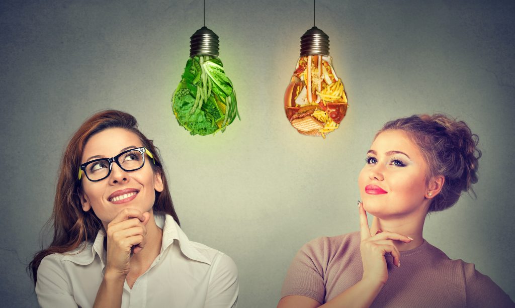 2 women looking at lightbulbs healthy vs unhealthy food